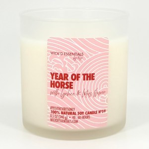 A white natural soy candle in a clear glass container, labeled 'Year of the Horse' with a pink background featuring swirls and floral designs.